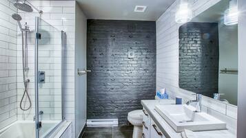 A modern bathroom with a glass-enclosed shower, a white sink, and a large mirror.