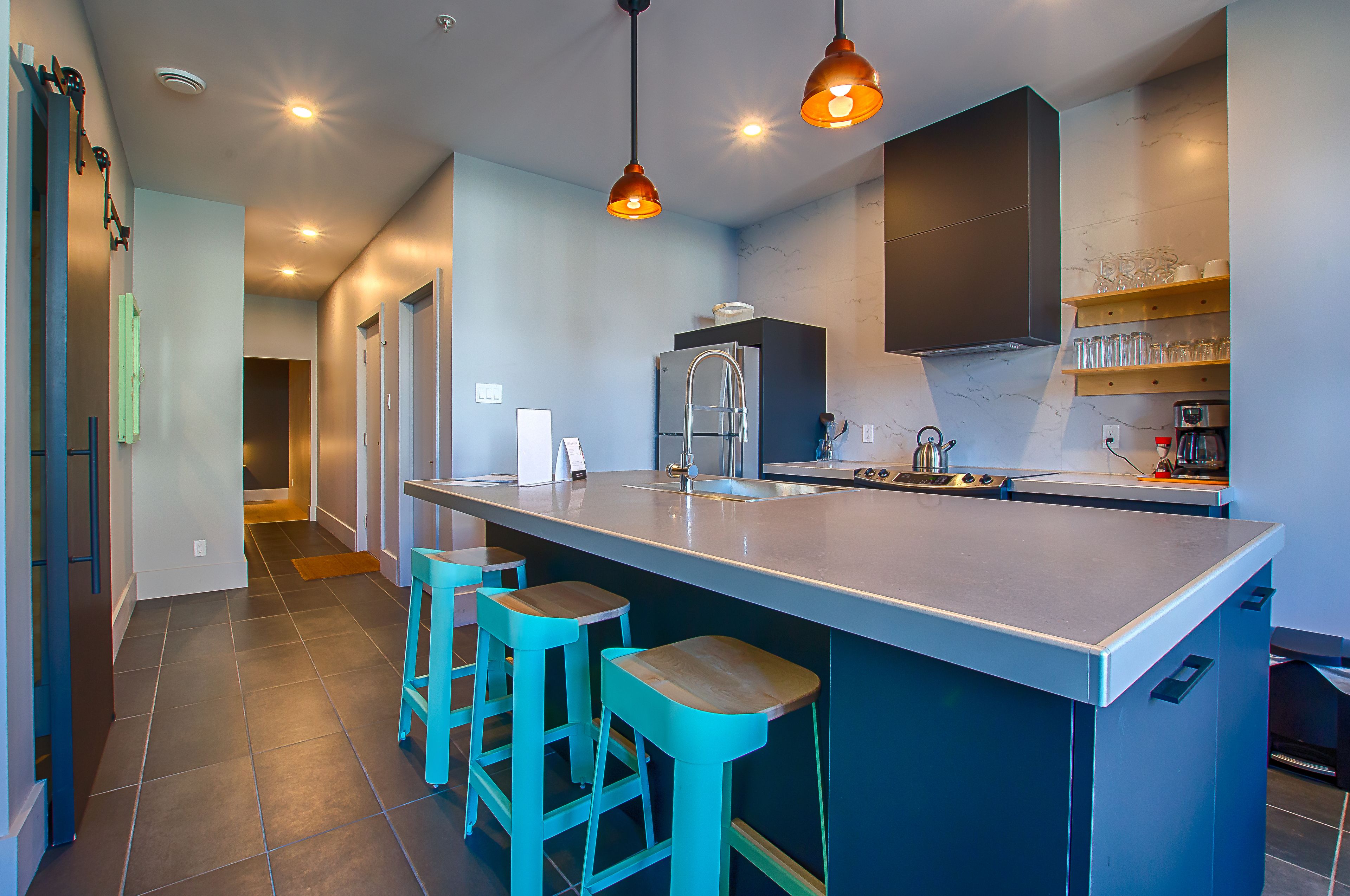 Uma cozinha moderna com uma ilha grande, banquetas e iluminação pendente.