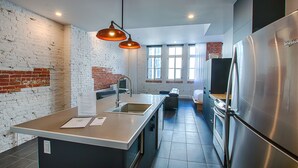 Una cocina moderna con un refrigerador de acero inoxidable, un horno empotrado y una isla grande con un lavamanos.