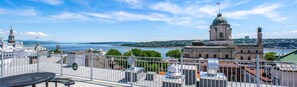 Hoher Aussichtspunkt mit Blick auf eine Stadtlandschaft, einen Fluss, historische Gebäude und einen Uhrturm.