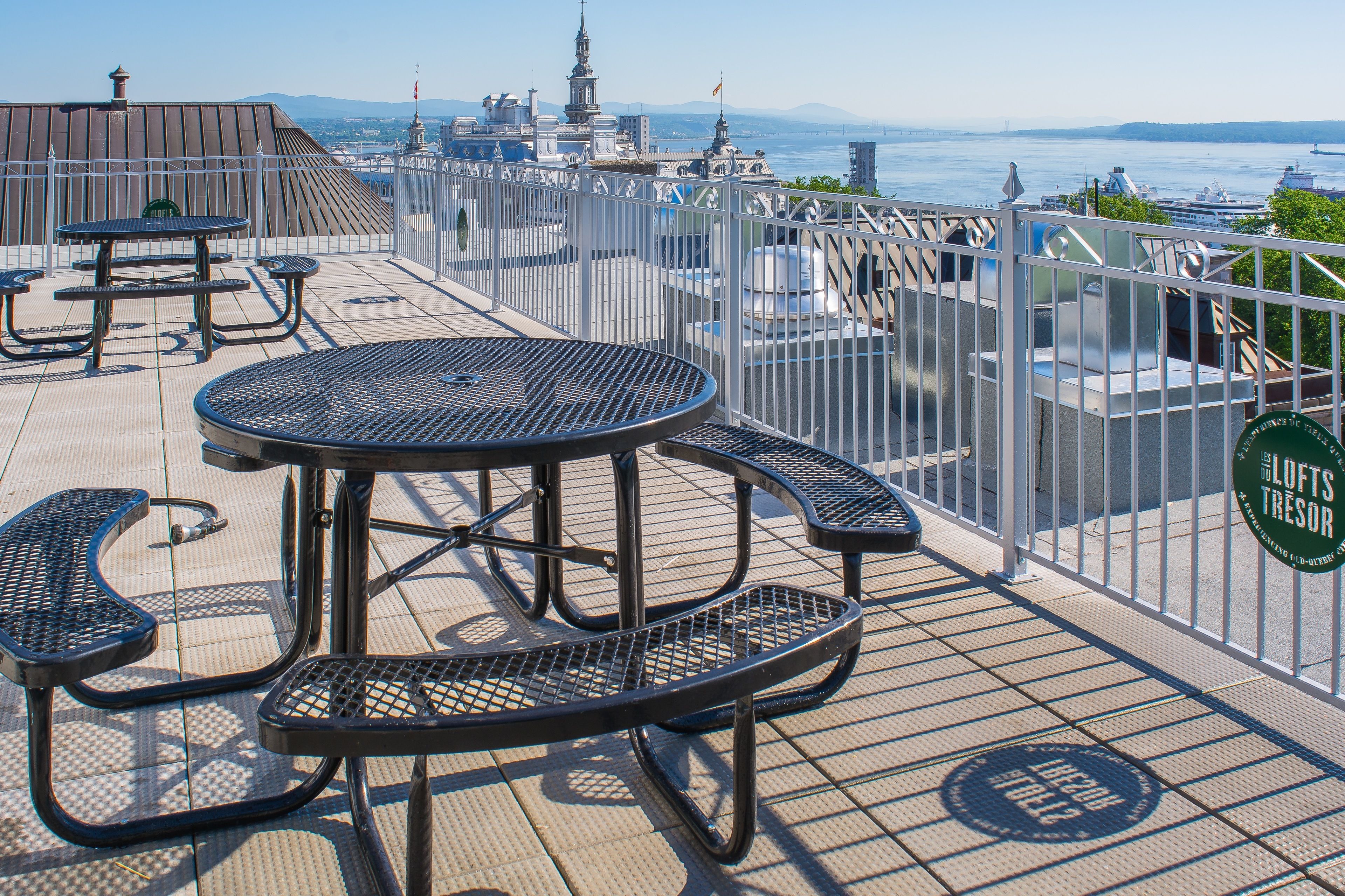 Terraza en la azotea con mesas de picnic y vistas de un horizonte urbano.