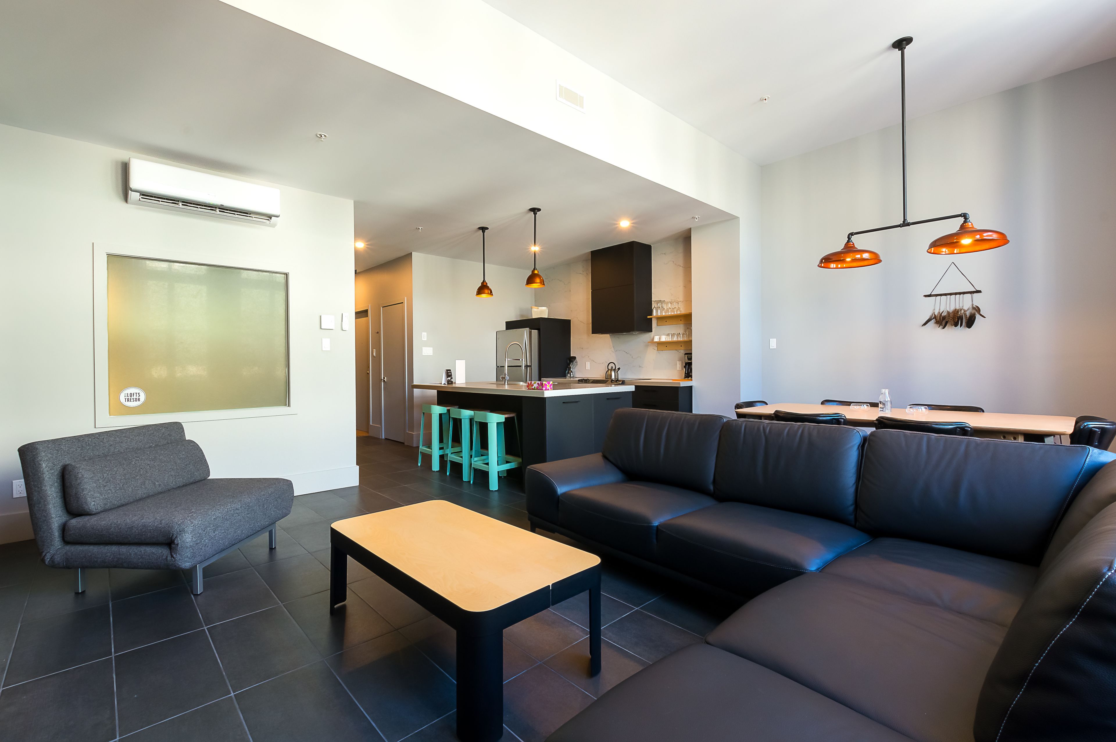A modern living room with a sofa, a small table, and a kitchen area in the background.