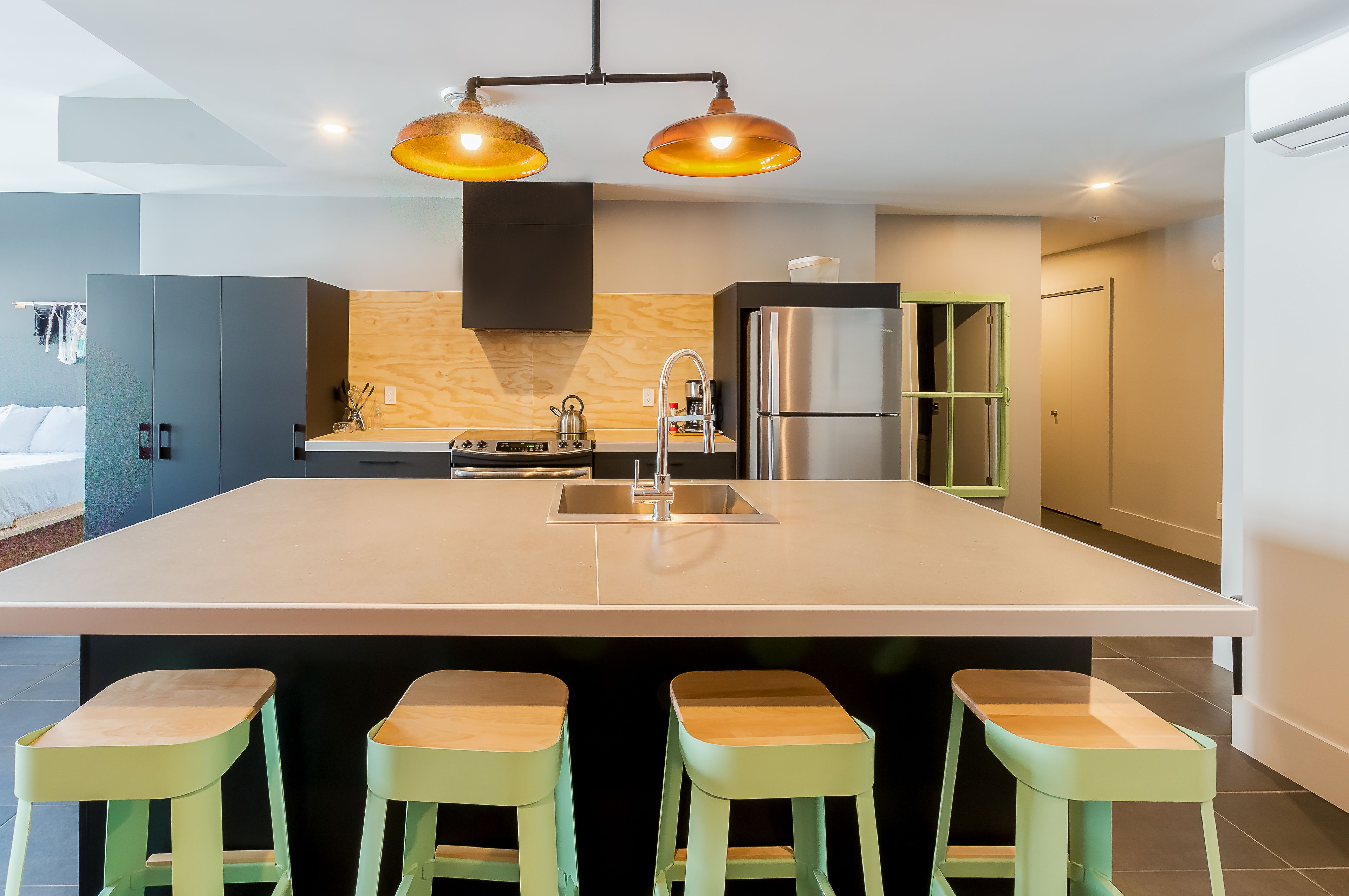 Cozinha moderna com uma ilha grande, duas luminárias pendentes e banquetas de bar.