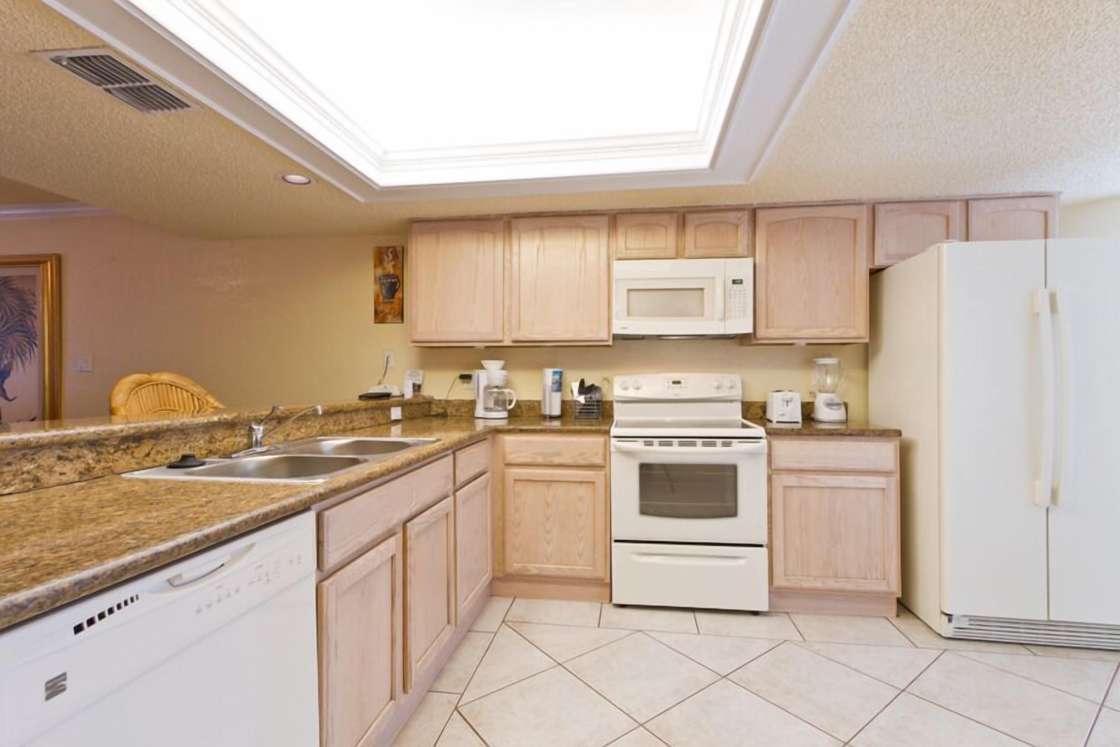 Una cocina con gabinetes de madera, microondas, estufa y lavavajillas.