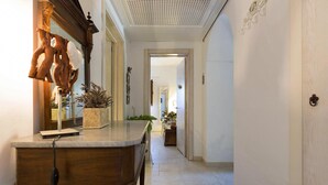 Um corredor com um aparador de madeira, um espelho e uma planta.
