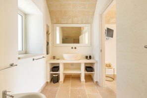 Une salle de bain moderne avec un grand lavabo, un miroir et une petite table.