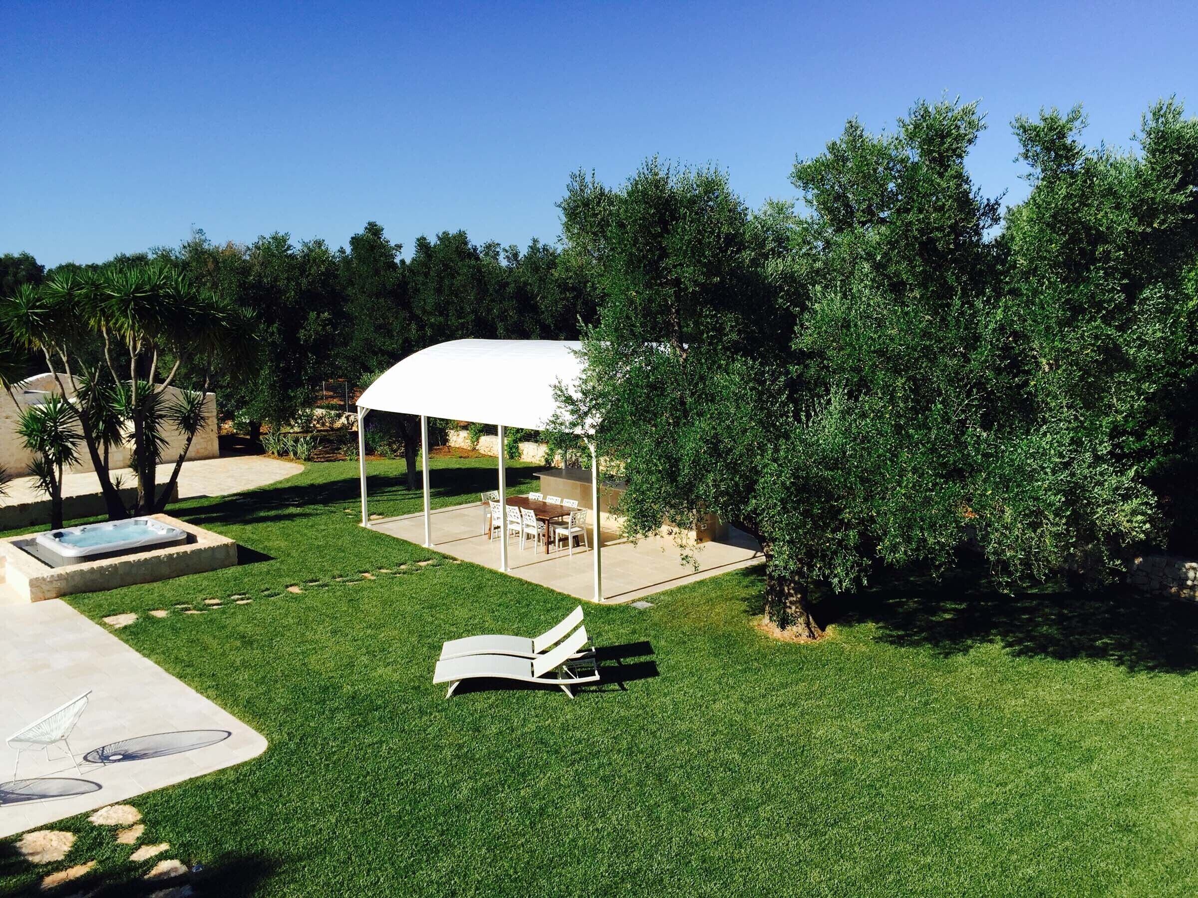 A covered patio area with a pool, lounge chairs, and a barbecue grill.