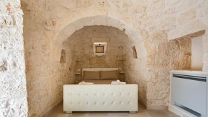Un dormitorio con pared de piedra, una cama, un ventanal pequeño y un armario empotrado.