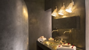 Un baño moderno con un espejo grande, un lavabo con artículos de aseo y un perchero para toallas.