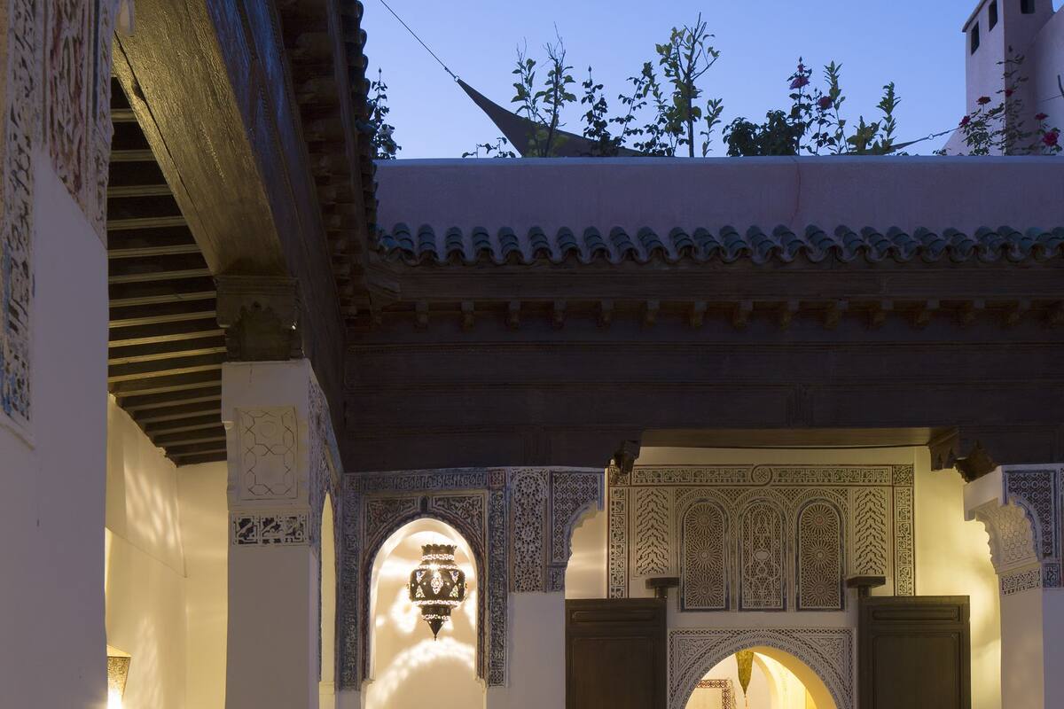 A traditional courtyard with ornate arches and a balcony with a wrought iron railing.