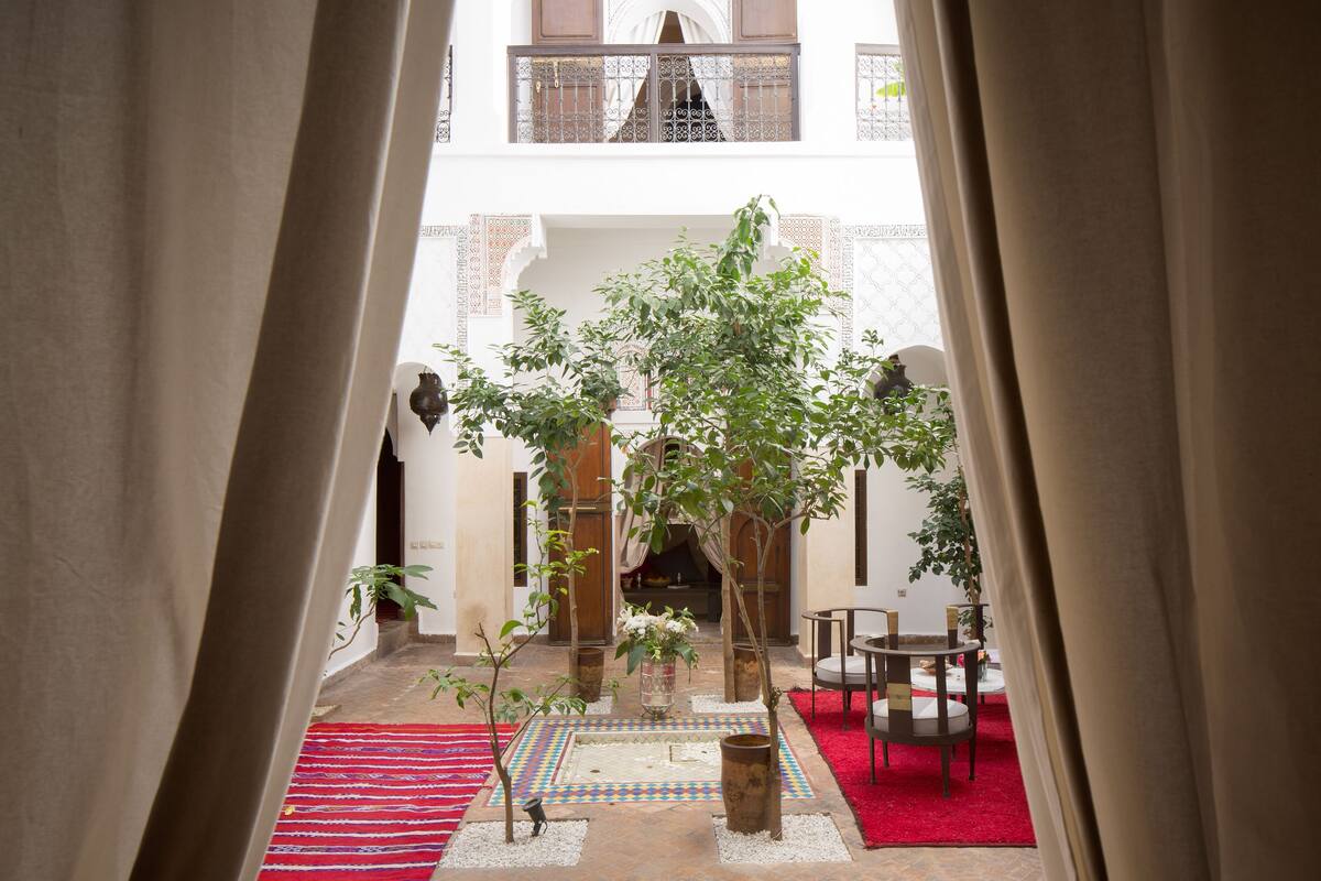 An indoor courtyard with a red carpet, potted plants, and a seating area.