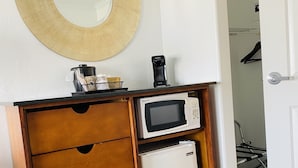 A kitchenette with a microwave, coffee maker, and storage drawers. - The Pines Country Inn (Owosso)