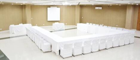 A large conference room with a long table and chairs, a whiteboard, and a neutral color scheme.