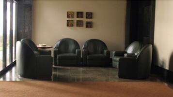 A lobby with two leather armchairs, a small table, and a tiled floor.