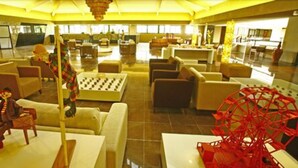 A spacious lobby with multiple seating areas, a large checkered table, and a prominent red Ferris wheel. - Garden Hotel Campina Grande (Campina Grande)