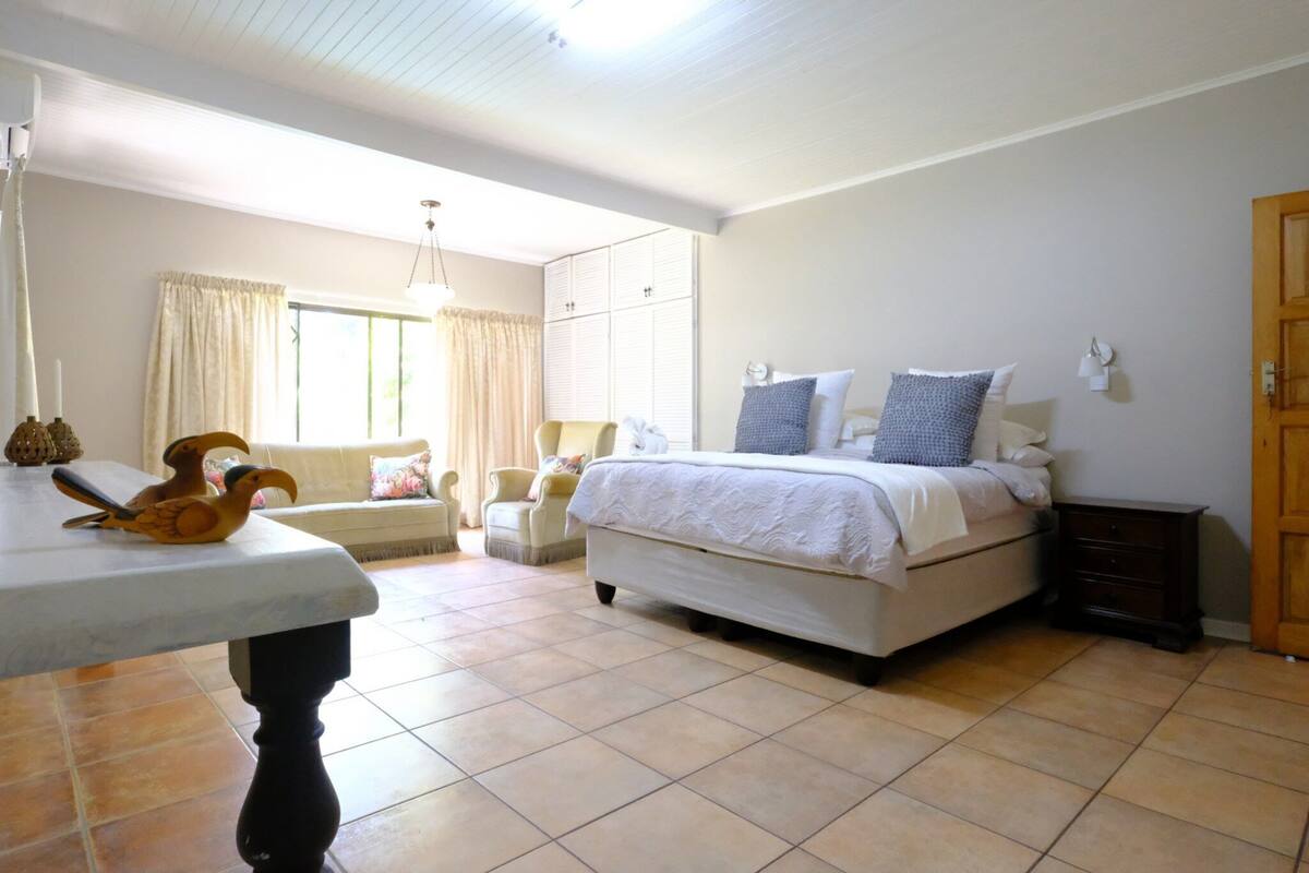 A bedroom with a bed, bedside tables, a chair, a window with curtains, and a door.