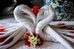 A bed with white towels arranged in a heart shape, surrounded by red and white flowers. - Santa Lucia Guest House (St. Lucia)