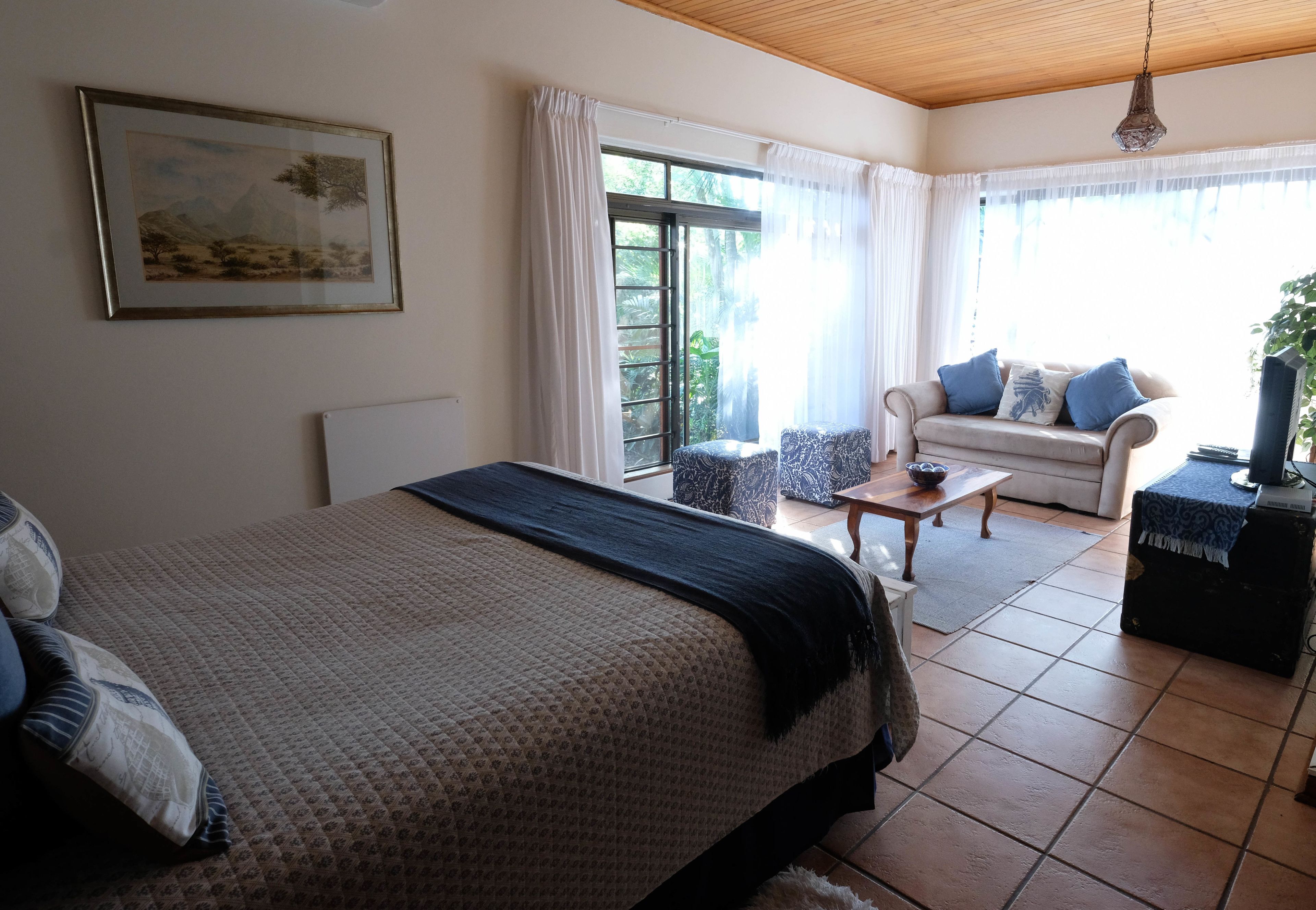 A bedroom with a bed, a sofa, a coffee table, and a TV.