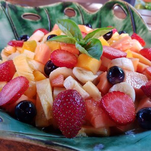 A fruit salad with strawberries, blueberries, and melon pieces, garnished with a basil leaf. - Santa Lucia Guest House (St. Lucia)
