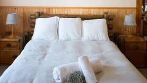 A neatly made bed with white linens, two bedside lamps, and a wooden headboard.