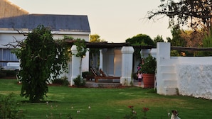 A well-maintained garden with a lawn, a wooden bench, and a white wall.