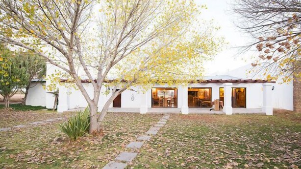 A building with a white exterior, a covered patio area, and a stone pathway leading to the entrance.