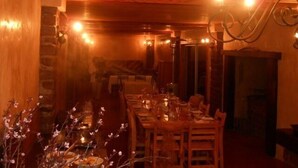 A warmly lit dining area with wooden walls and a stone fireplace.