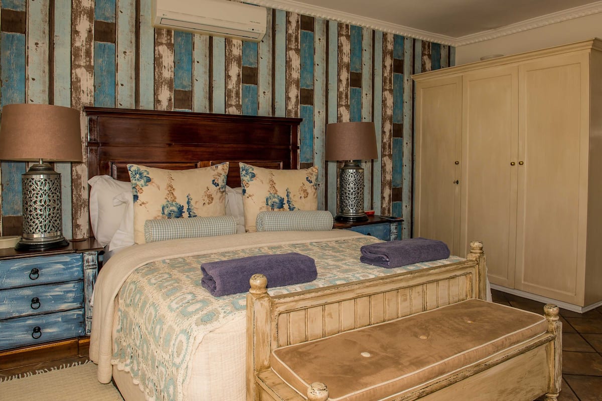 A bedroom with a wooden bed, two nightstands, a wardrobe, and a small table.