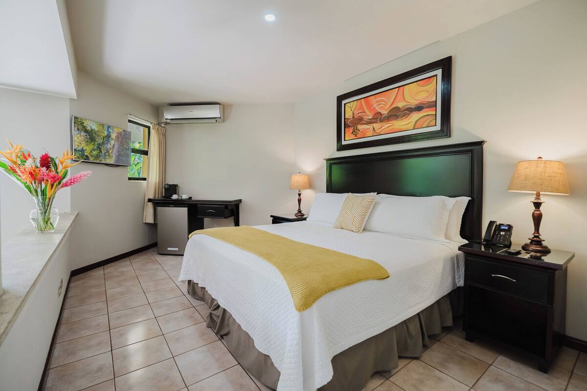 Une chambre d’hôtel avec un lit, des tables de chevet, un bureau et une chaise.