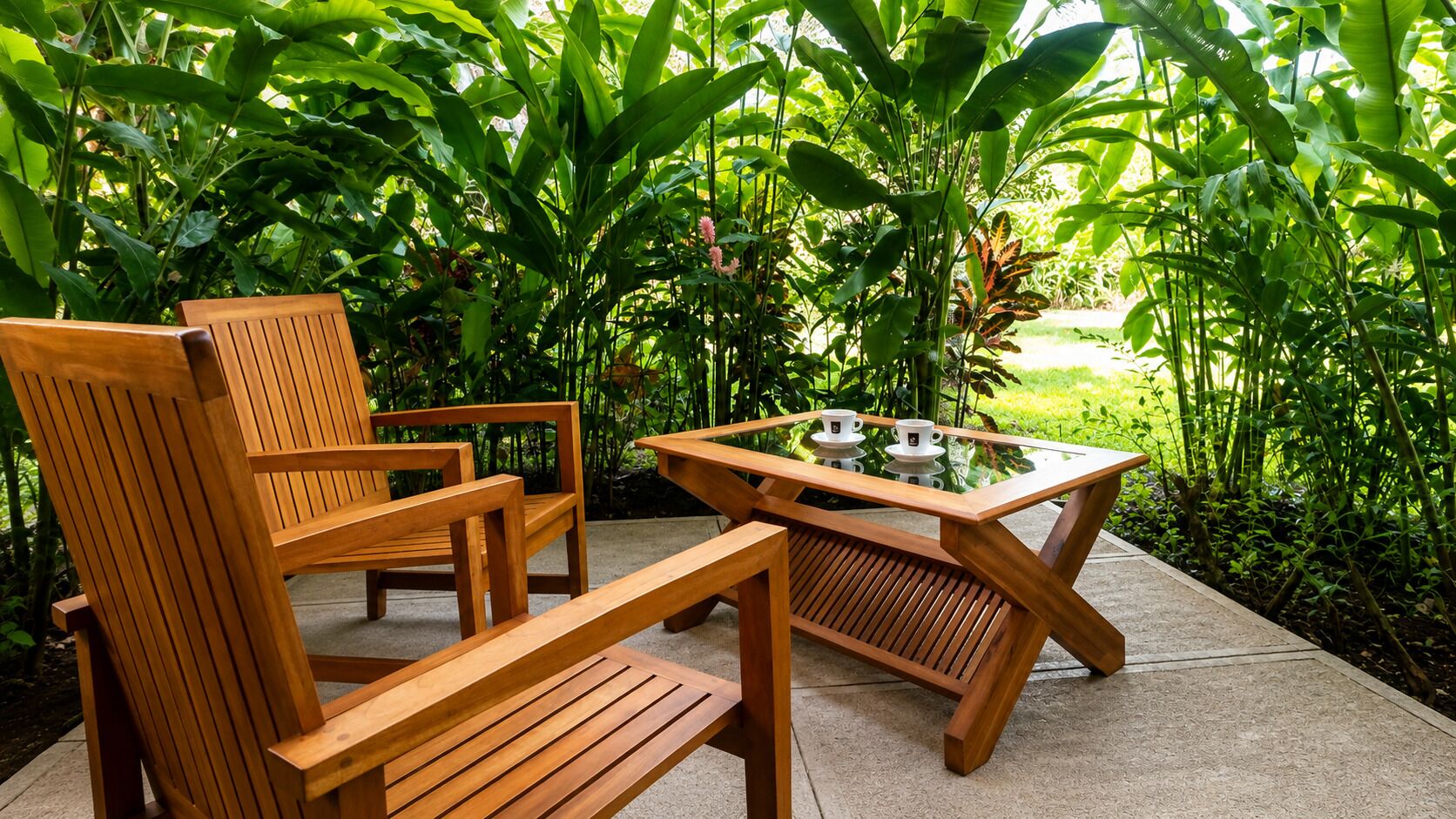 A wooden outdoor seating area with chairs and a table, surrounded by lush greenery.