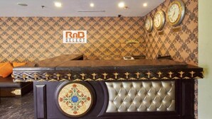 A reception area with a dark reception desk, a patterned wallpaper, and three wall clocks. - RnB Banjara Hills (Hyderabad)
