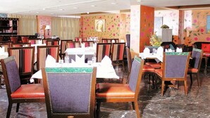 A restaurant with multiple tables and chairs, some with cushioned seats. - RnB Banjara Hills (Hyderabad)