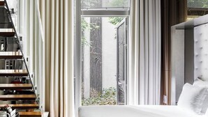 Una habitación de hotel moderna con una cama, un escritorio y una escalera.