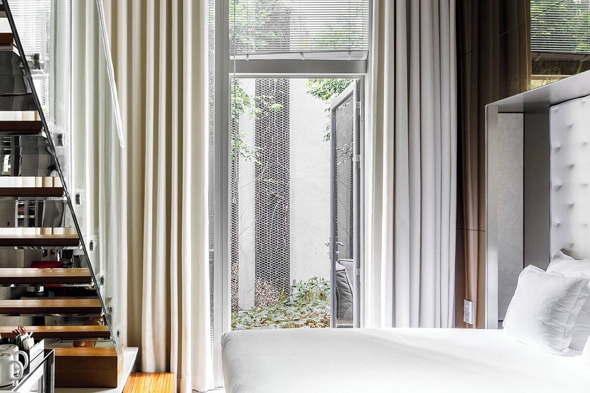 Een moderne hotelkamer met een bed, bureau en een trap.
