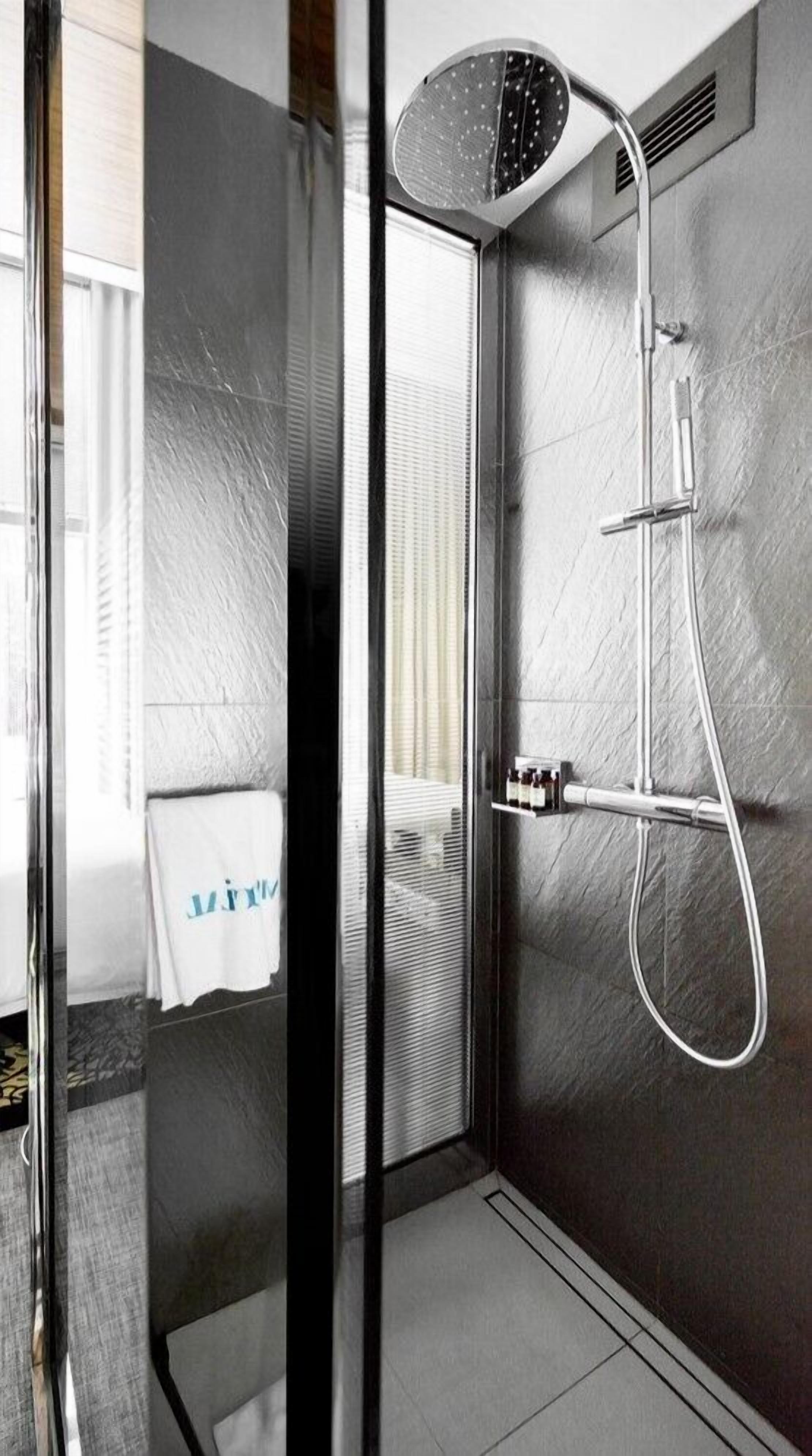 A modern shower with a handheld showerhead and a wall-mounted control panel.