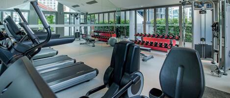 Un gimnasio con cintas de correr, bancos de pesas y mancuernas.