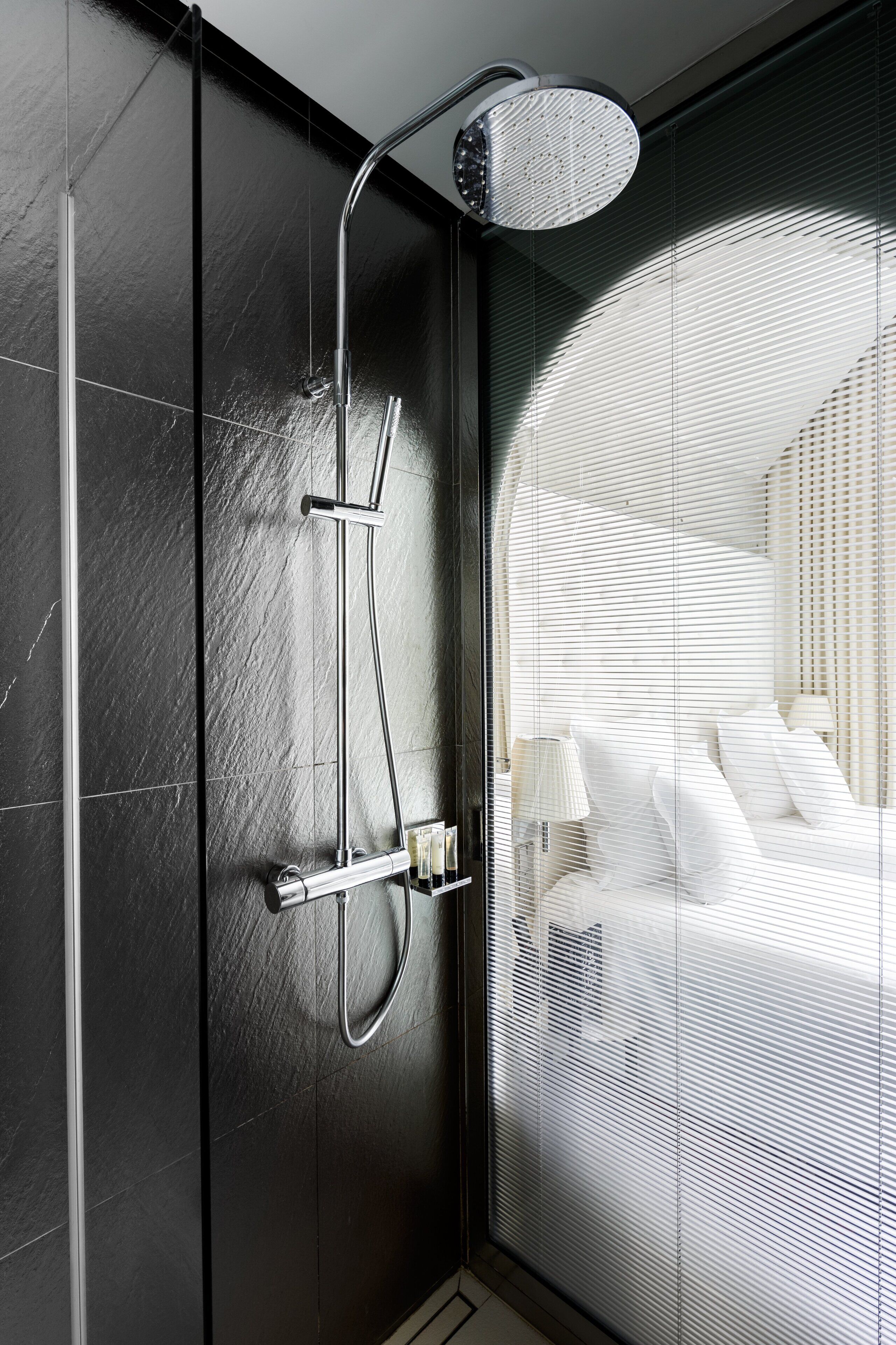 A modern bathroom with a glass shower enclosure, a handheld showerhead, and a wall-mounted faucet.
