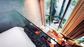 Una habitación de hotel moderna con un separador de vidrio, un conjunto de sofás y vistas al exterior.