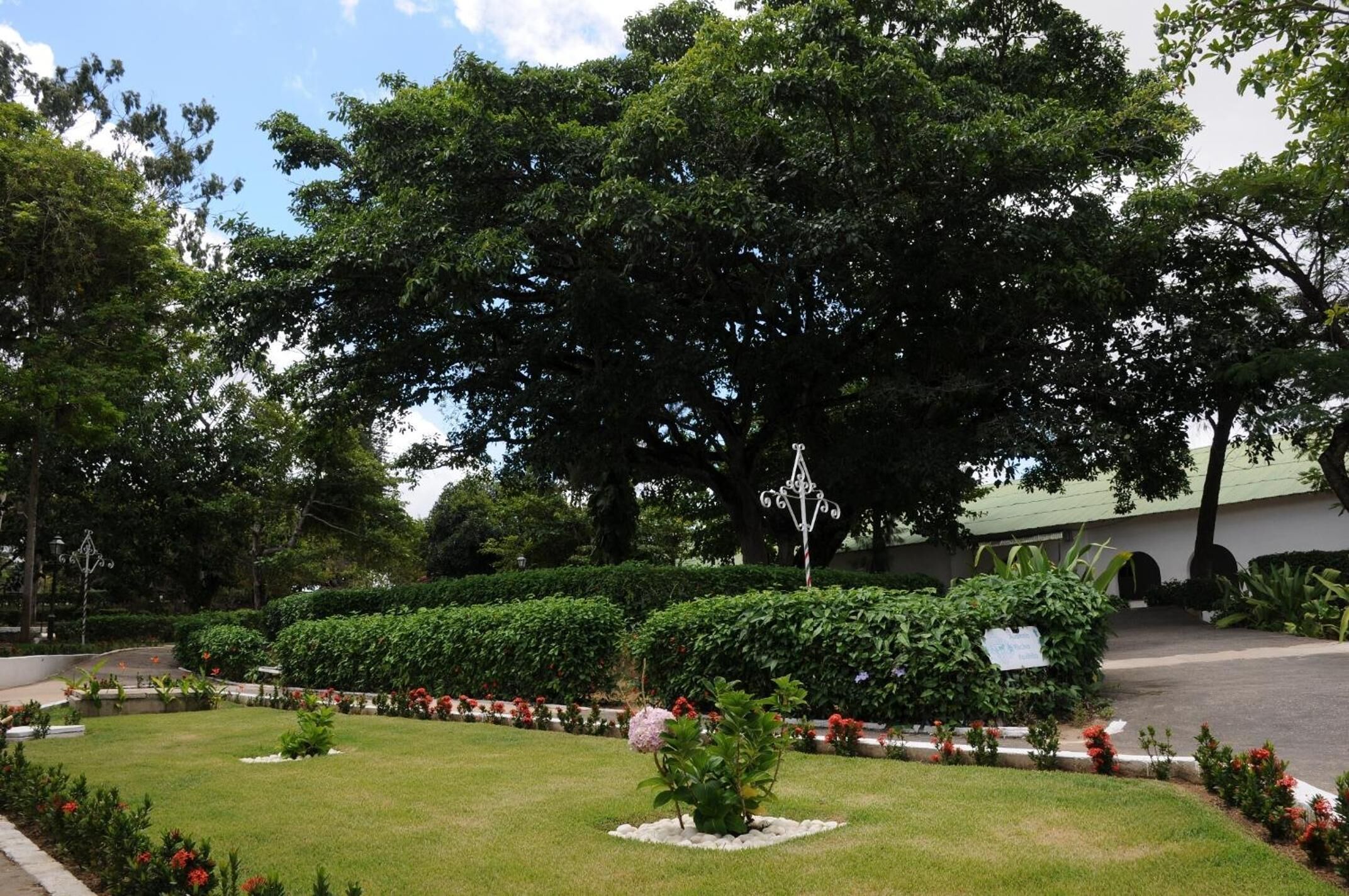 A well-maintained garden with a variety of plants and flowers, a central decorative structure, and a paved pathway.