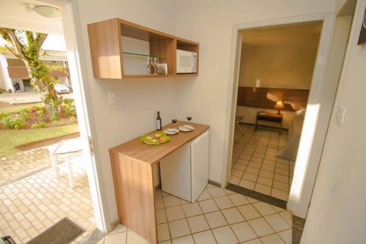 Une cuisine compacte dotée d’un plan de travail en bois, d’un four à micro-ondes et d’un petit réfrigérateur.
