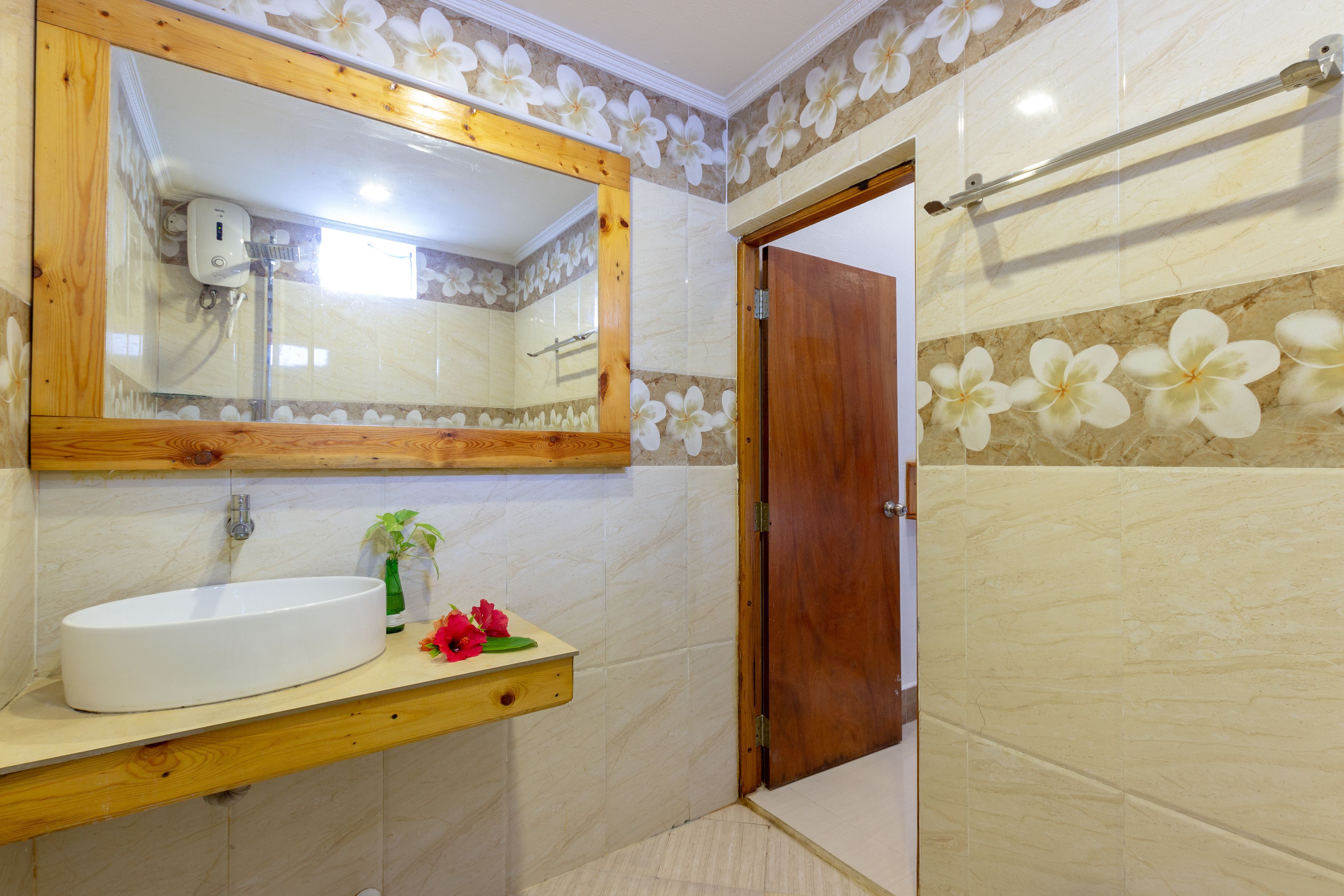Baño con tocador de madera, un espejo grande y zona de ducha.