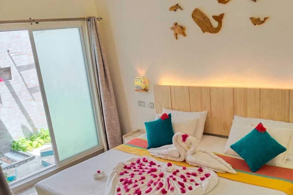 A hotel room with a wooden bed, a large window, and a wall decorated with wooden animal figures.
