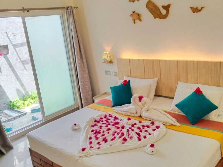 A hotel room with a wooden bed, a large window, and a wall decorated with wooden animal figures.