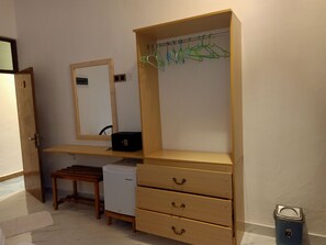 A room with a wooden desk, a mirror, a small refrigerator, and a blue trash bin. - Dream Inn Sun Beach Hotel (Thulusdhoo Island)