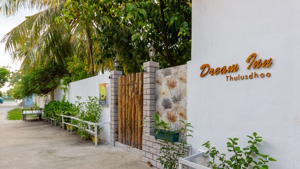 Una pared blanca con un letrero que dice 'Dream Inn Thuludhoo'.
