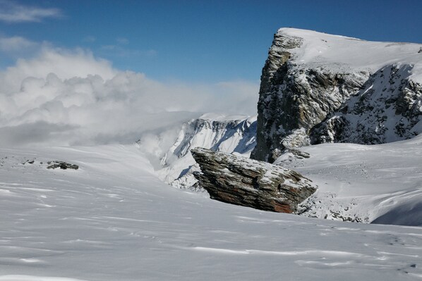 A snow-covered mountain landscape with a prominent rock formation.