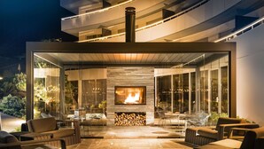 An outdoor patio with a fireplace, seating area, and glass walls. - 7132 Hotel (Vals)