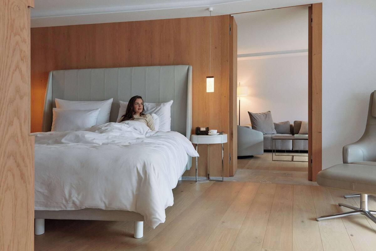 Une chambre moderne avec un grand lit, une table de chevet et un coin salon comprenant un canapé et un fauteuil.