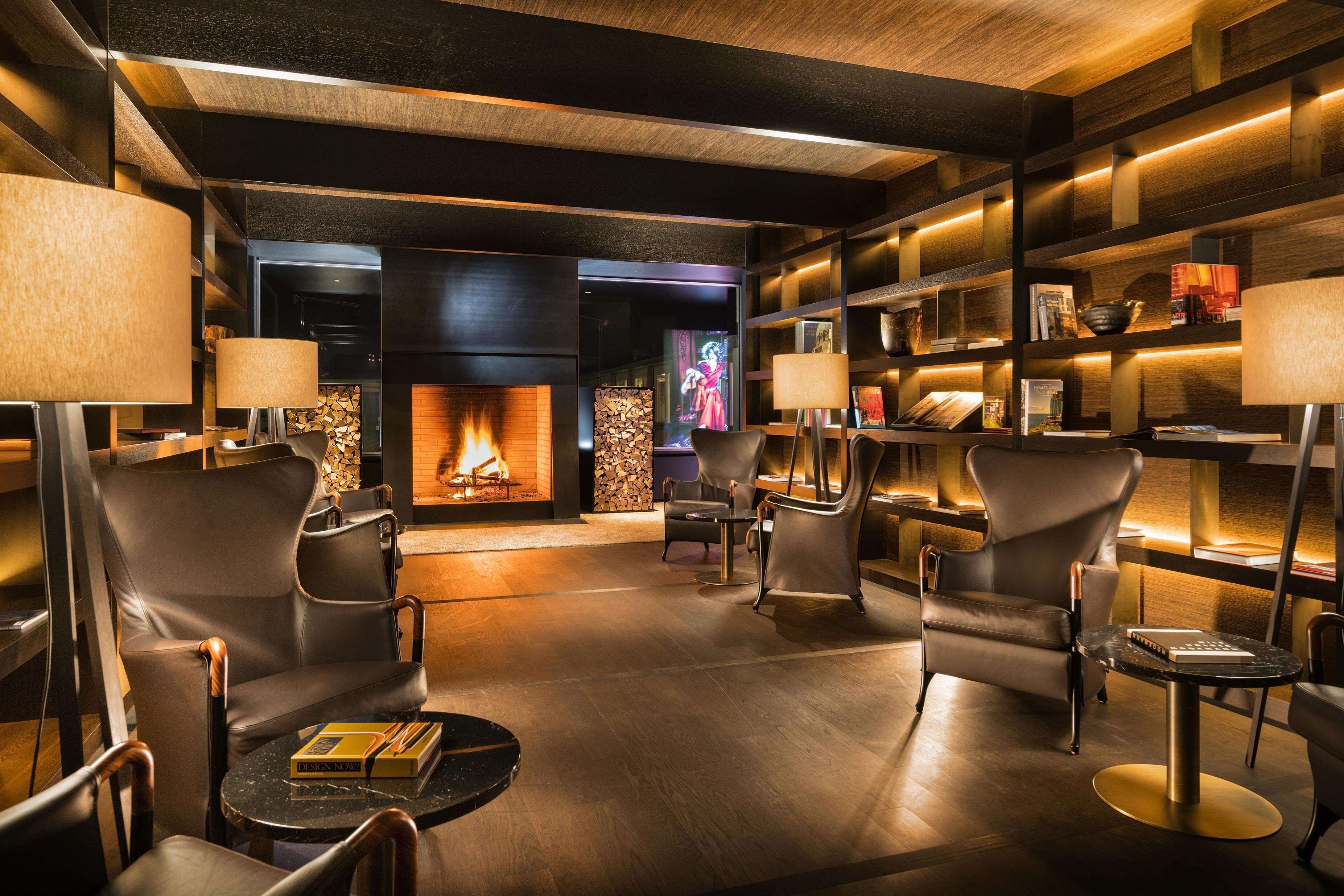 Un área de descanso moderna con sillones de cuero, chimenea y estanterías.