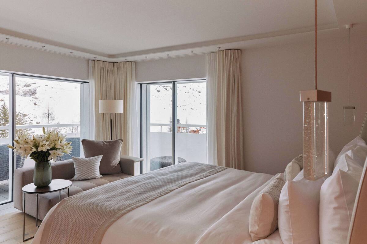 Une chambre d’hôtel moderne avec un grand lit, un canapé, une petite table et un vase de fleurs.